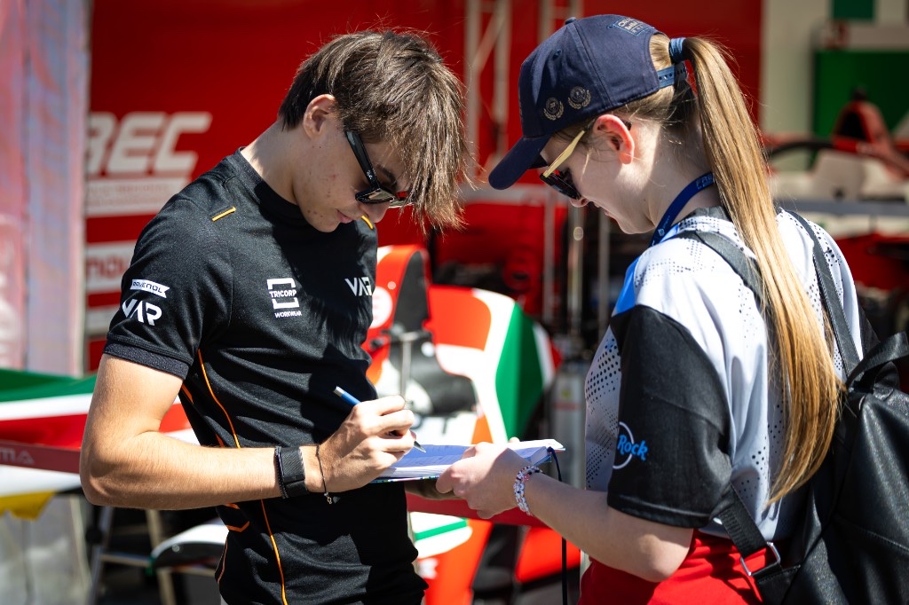 Andrea Dupé signing an autograph for a fan in the paddock