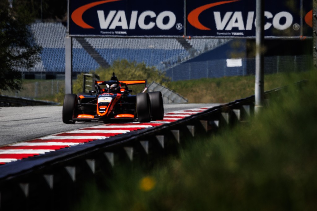 Andrea Dupé on the straight at Spielberg — VAICO banner overhead